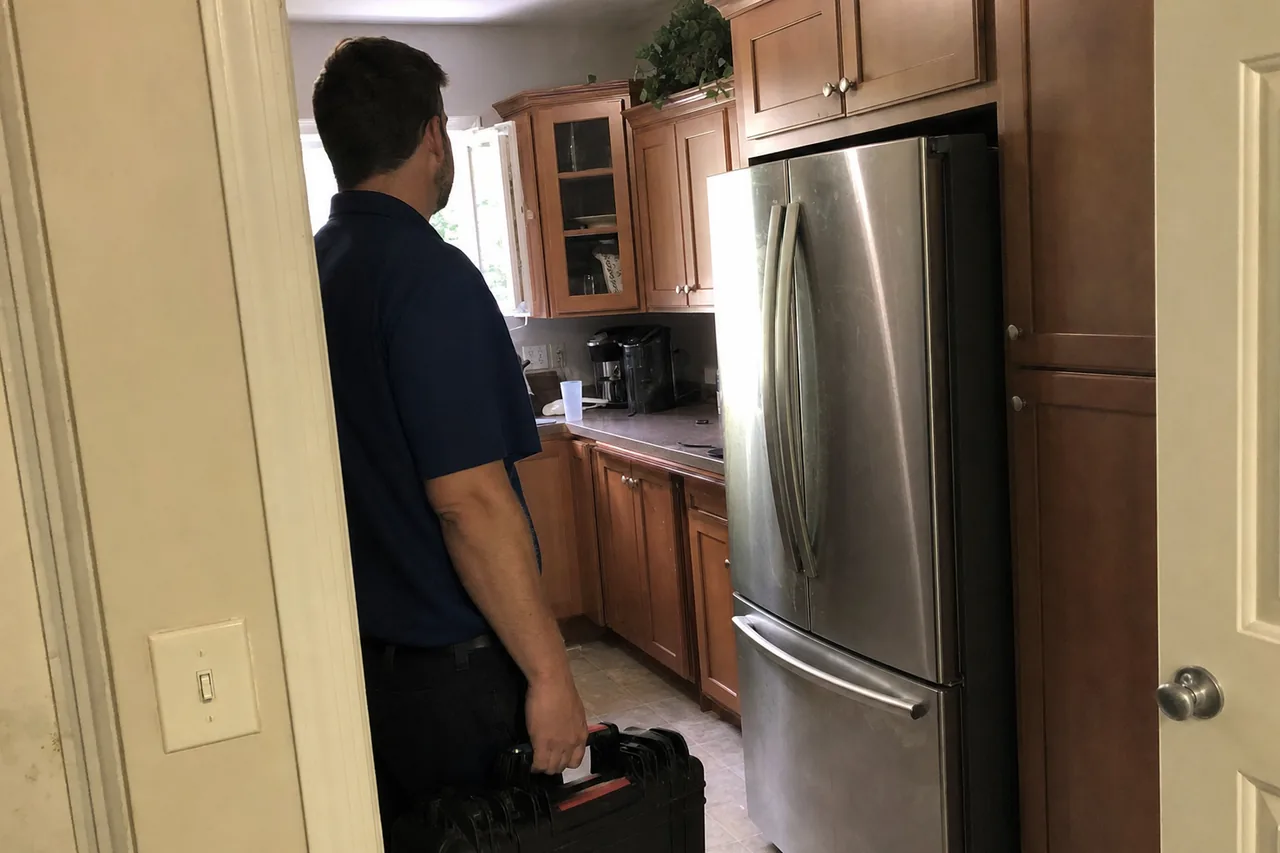 A technician arriving through the doorway of a Jacksonville kitchen with a hard tool case in his hand