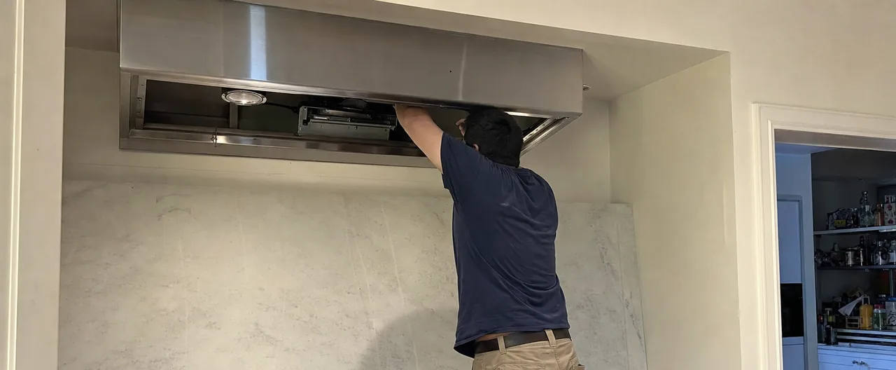 The same hood service mirrored - the canopy open, the blower housing visible and the filters set aside